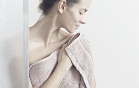 Woman patting her skin dry after showering.