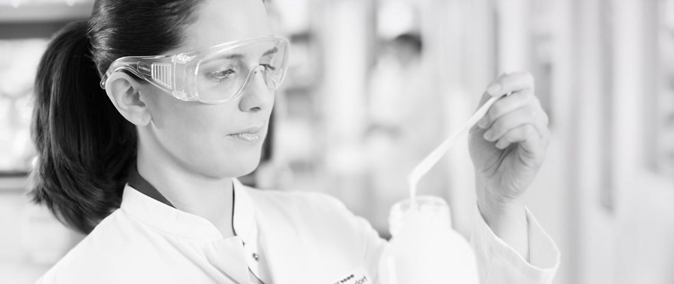 Female scientist with safety goggles testing a formula