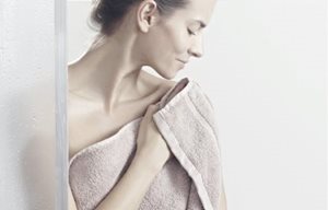 Woman patting her skin dry after showering.