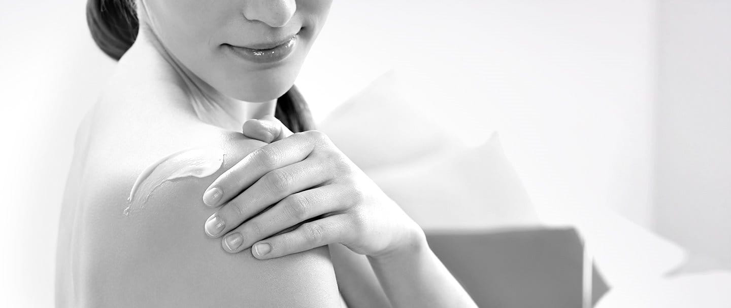 Woman applying cream on her shoulder
